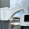 A large PTZ camera made by Uniview mounted at the corner of a building using a white metal corner bracket