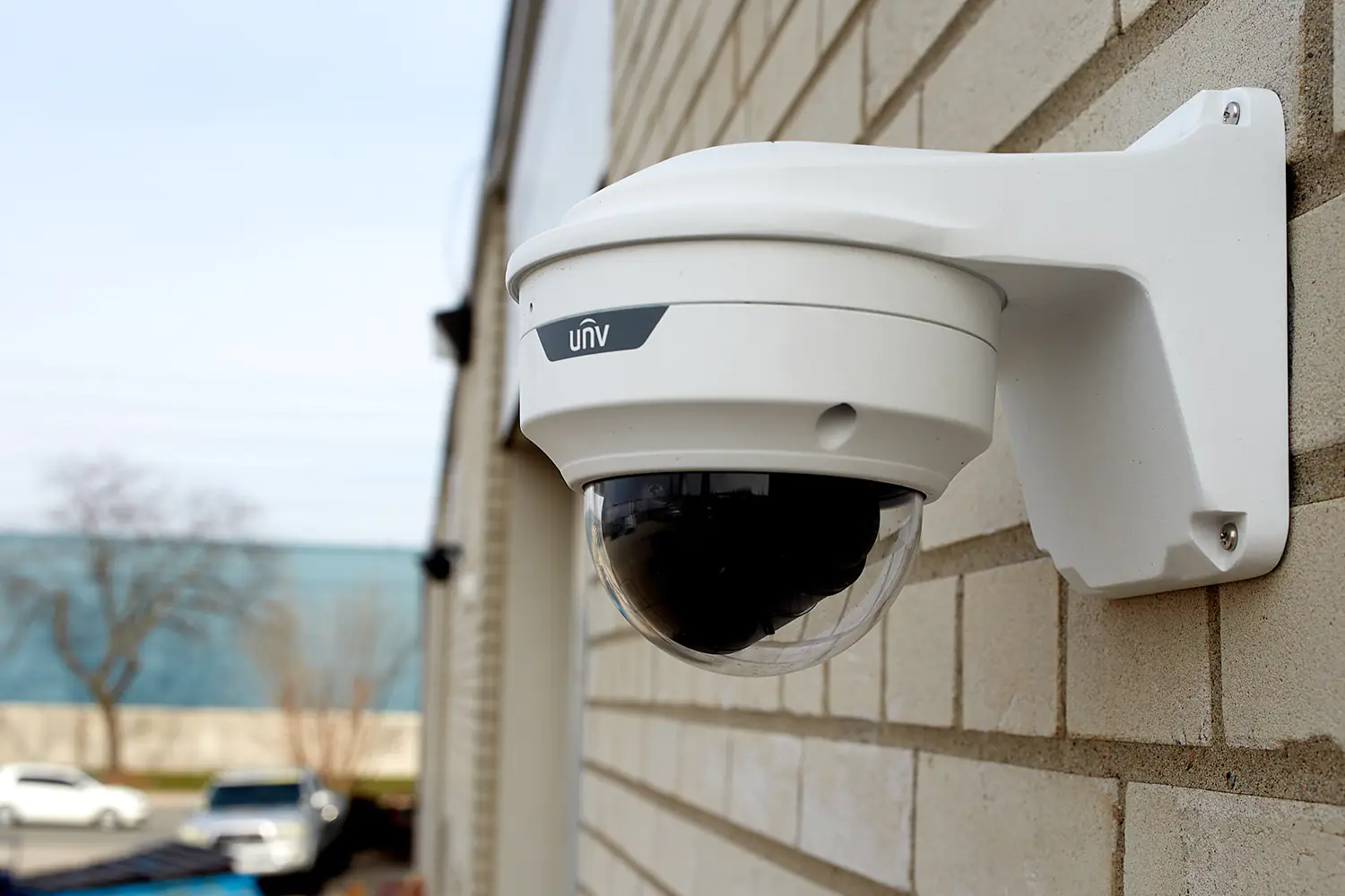 Uniview AE-TR-WM03-D-IN Junction box mounted on a wall, with a camera underneath, in a parking lot