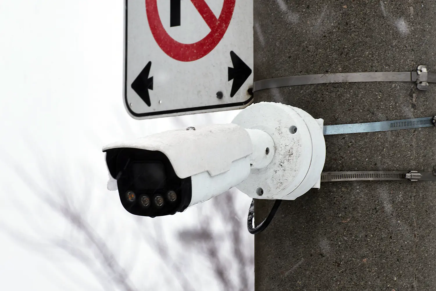 Security camera mounted on a pole using a metal bracket, on a snowy day