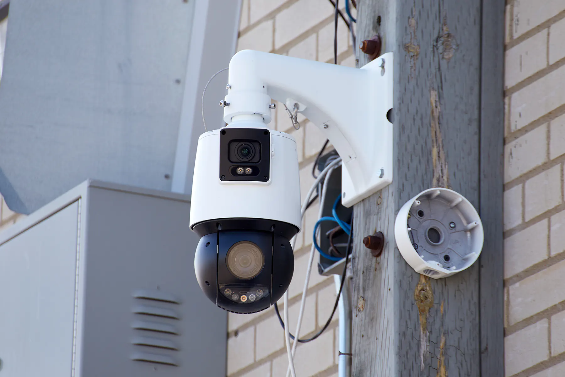 PTZ Security camera mounted to a wooden post on the side of a commercial building