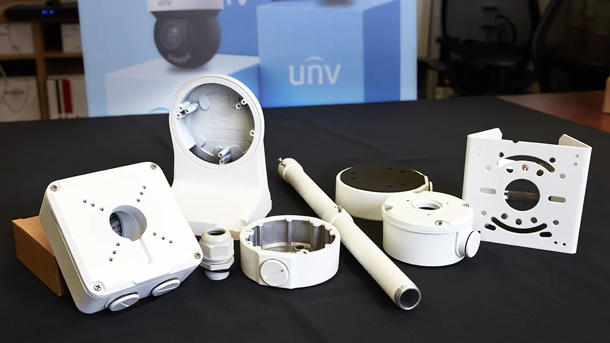 A variety of camera mounting brackets on a table with a black cloth underneath. A sign that says UNV can be see in the background.