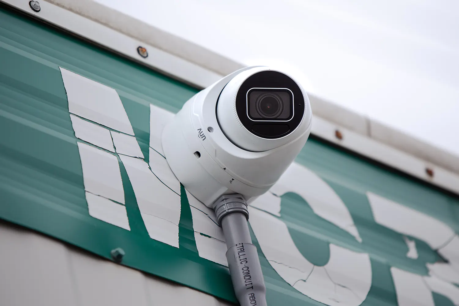 A security camera installed on the side of a trailer with conduit protecting the wiring.