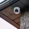 A white security camera installed underneath the soffit of a house with the sky in the background