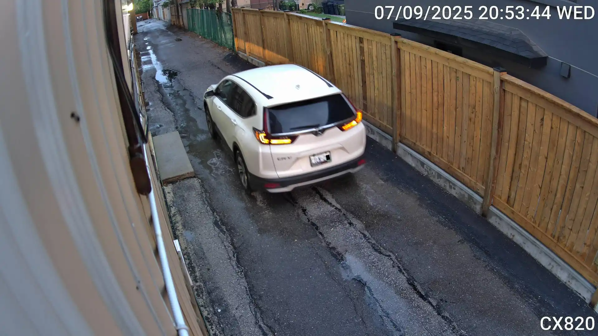 A snapshot of a vehicle taken by a security camera. The license plate is slightly blurry due to low lighting in the evening.