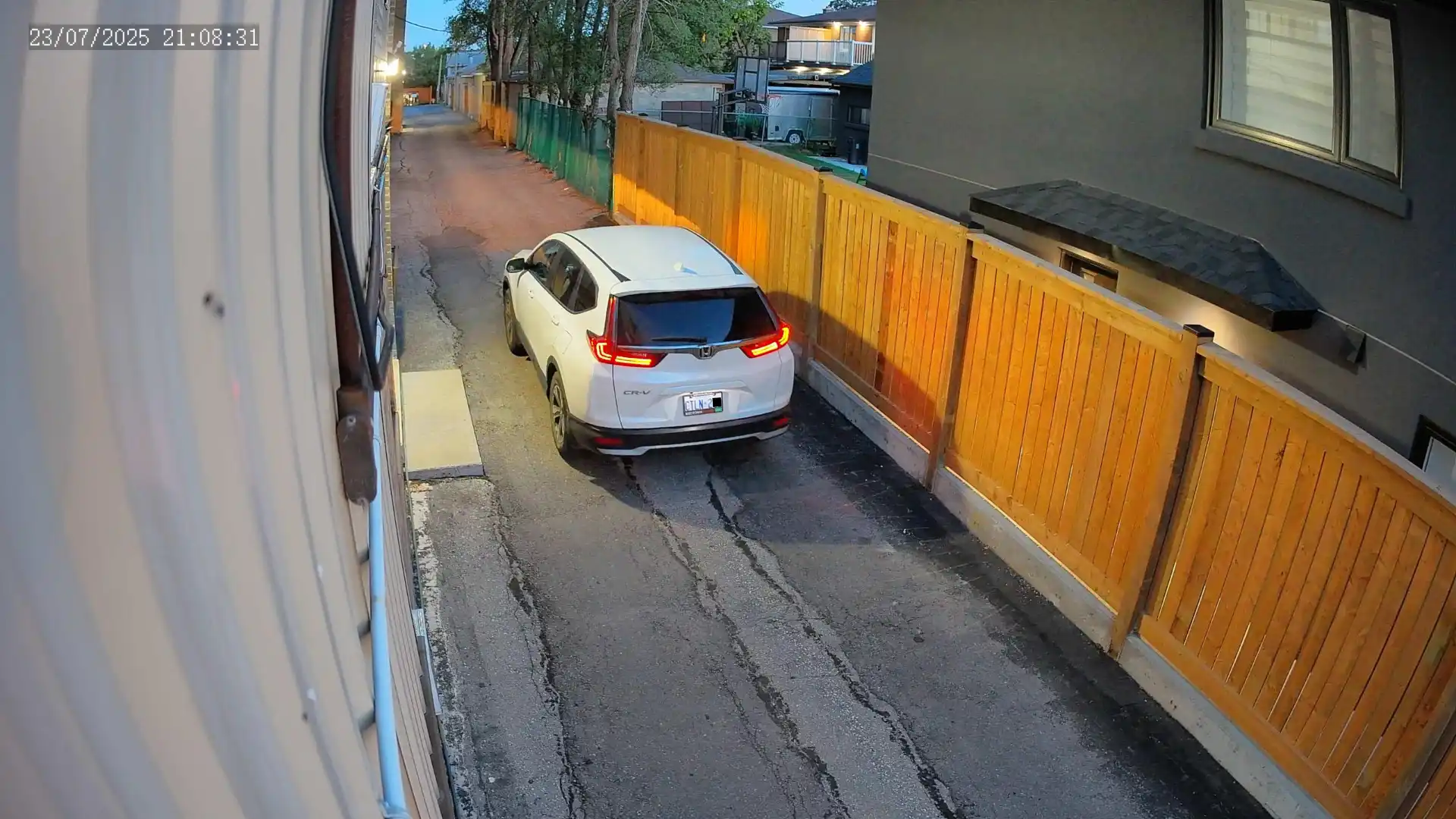 A snapshot of a vehicle taken by a security camera. The license plate is slightly blurry due to low lighting in the evening.