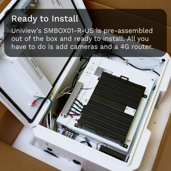 A top-down view of a white metal box with a black video recorder inside. Multiple wires are running alongside the inner-edge of the box, connecting the various components together.