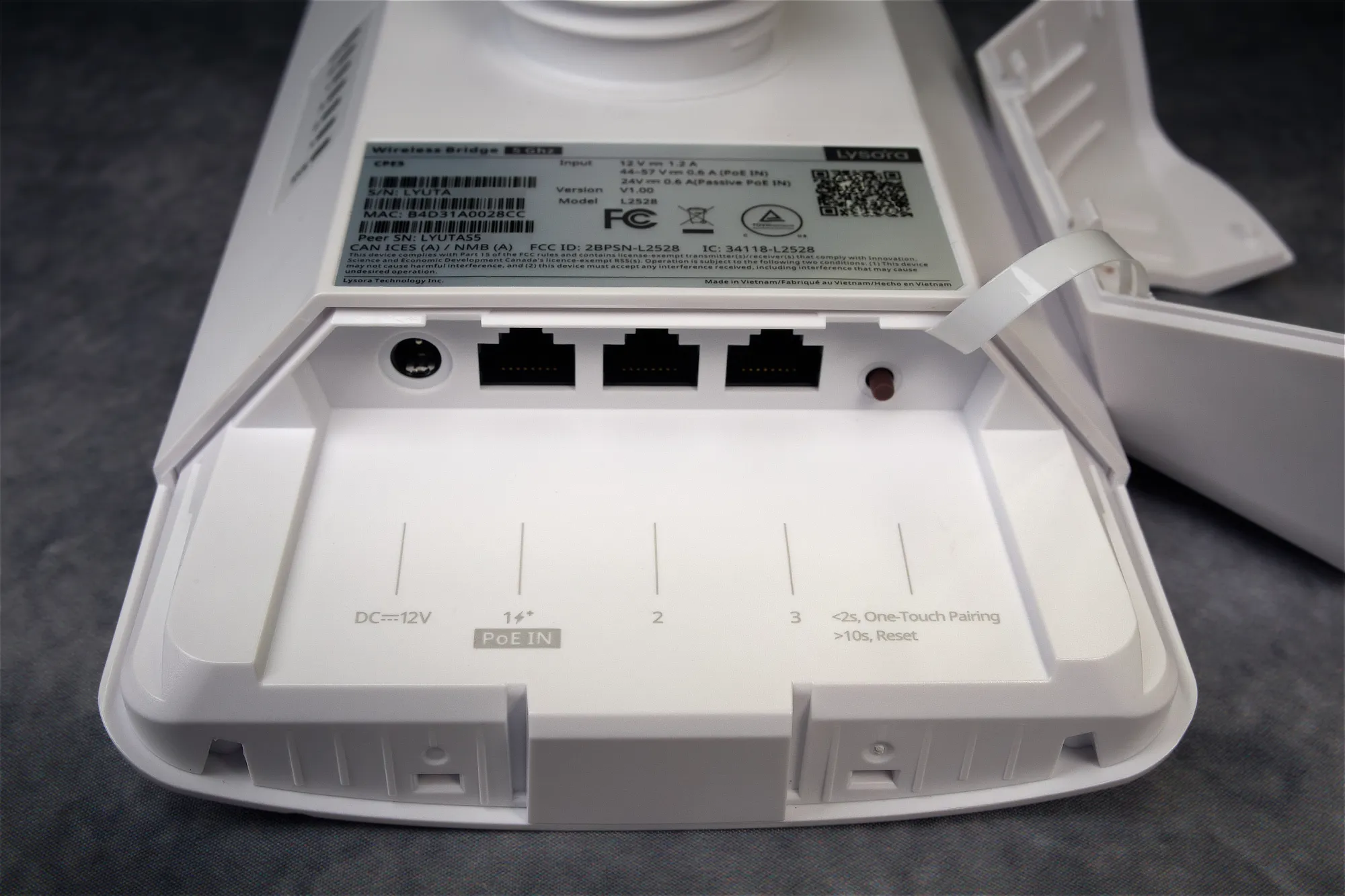 The bottom of Lysora's CPE5 wireless bridge, showing a 12V DC power input, three Ethernet ports, and a small brown button that functions as a one-touch pairing button, as well as a factory reset button if you hold it for more than 10 seconds.